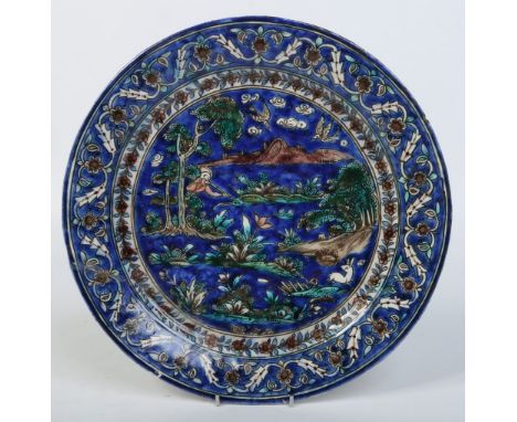 A 19th century Persian Iznik type earthenware dish. Blue ground and painted with a rabbit hunting scene under floral borders,