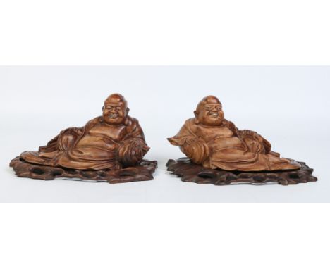 Two 19th century Chinese hardwood figures on pierced stands. Each carved in the form of Pu Tai having glass eyes and bone inl