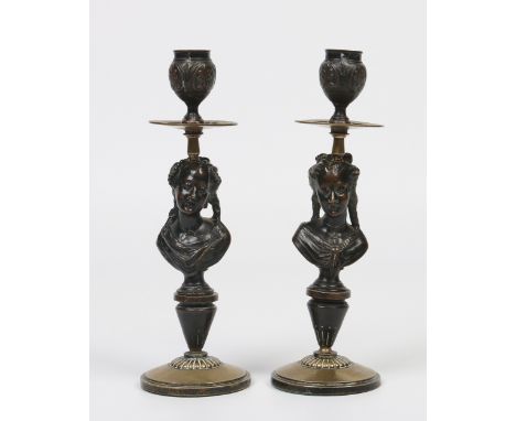 A pair of nineteenth century French patinated and parcel gilt bronze candlesticks. Each with a pedestal modelled in the form 