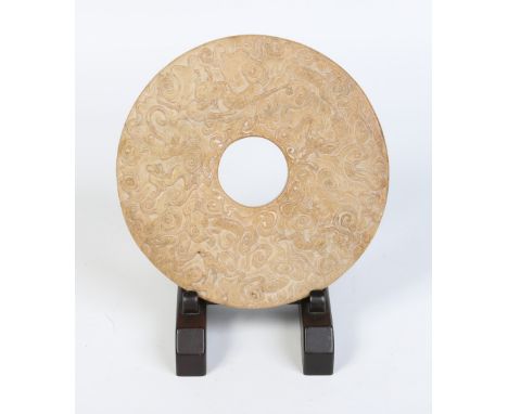 A 19th century Chinese carved soapstone bi disc on hardwood easel stand. Decorated with dragons on a ground of cloud scrolls 