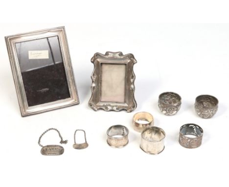 Ten pieces of hallmarked English silver. Including two eizel photograph frames, two decanter labels, four serviette rings and