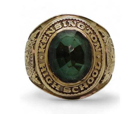 A 10k gold Metal Arts Brand American College ring, Kensington High School 1965, set with a green glass stone size S1/2, weigh