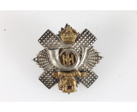 Unhallmarked white metal and gilt metal Highland Light Infantry cap badge of thistle and star form, 5cm tall, 28.5g gross. 