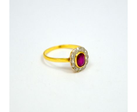 A RUBY AND DIAMOND CLUSTER RING, with central oval ruby within a surround of brilliant cut diamonds to the plain tapered band