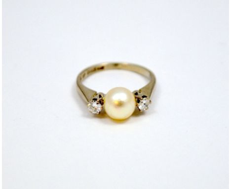 AN 18CT GOLD DIAMOND AND PEARL RING, the central pearl flanked by two brilliant cut diamonds to the plain tapered band, pearl