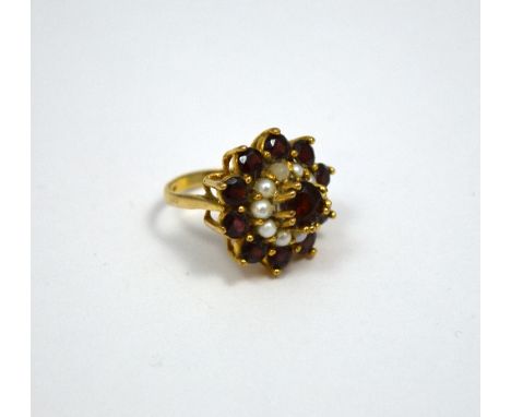 A 9CT GOLD DRESS RING, with central garnet within a surround of pearls to a further surround of garnets to the plain tapered 