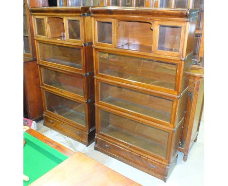 A pair of Globe-Wernicke-style mahogany and stained wood sectional bookcases, each with four sections, the upper having a pai