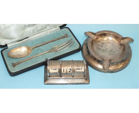 A seal-top spoon and fork in fitted case, London 1929, a small engine-turned desk calendar, 10cm wide, London 1926 and a load