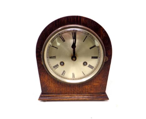 A 20th century dome topped oak cased mantel clock with silvered dial, pendulum and key 