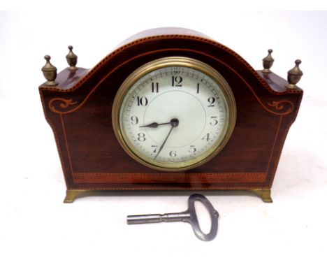 A late 19th century French inlaid mahogany mantel clock on raised brass feet with brass finials, with key.