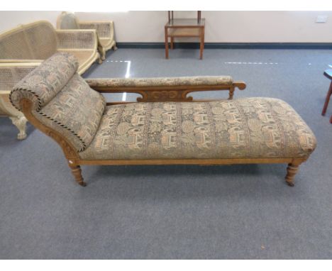 A late 19th century carved oak chaise longue upholstered in a tapestry fabric