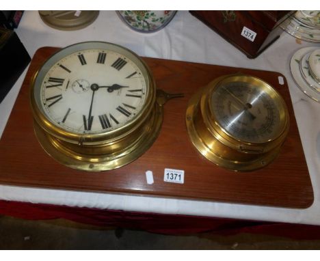 A brass ship's clock and a brass ship's barometer on wooden back board