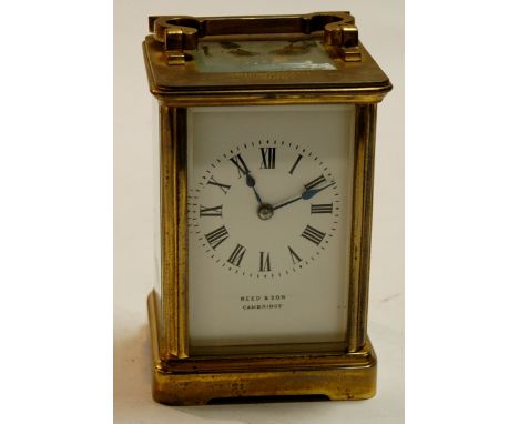 An early 20th century lacquered brass cased carriage clock, the white enamel dial with Roman numerals, signed Reed & Son of C