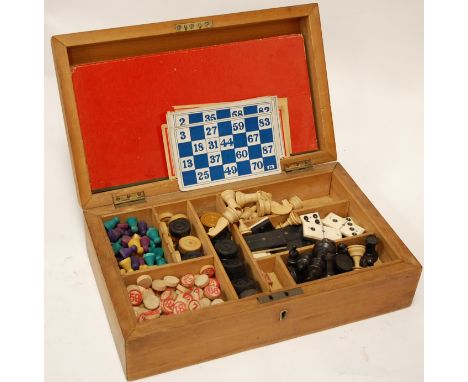 An early 20th century pine cased games compendium to include chess and draughts pieces etc