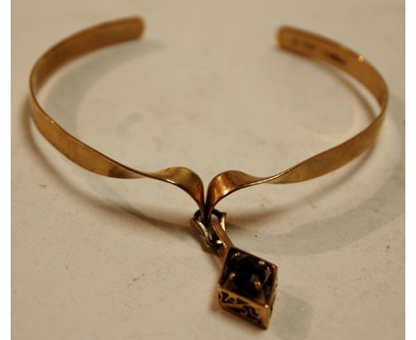 A modern 9ct gold bangle with garnet set pendant, 9.8g