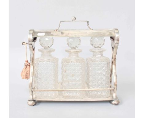 A Victorian Silver Plate Three-Bottle Tantalus, Late 19th Century, of typical form, engraved with initials 'JB' within a foli