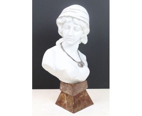 Ceramic bust of a female with pensive expression, wearing a silver necklace, raised on a marble effect pedestal base, approx 