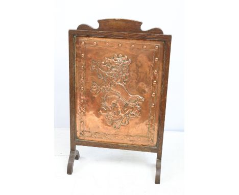 Early 20th century fire screen, the embossed copper panel decorated with a lion rampant, with oak surround, 70cm high x 42cm 