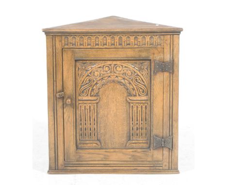 A 17th Century style oak hanging corner cupboard, 20th CenturyWith a chiseled frieze above a single carved door mounted on ir