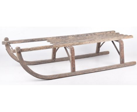 A vintage wooden sledgeOf traditional form with slatted top and arched lower rails, applied with metal mounts, 102cm long. 