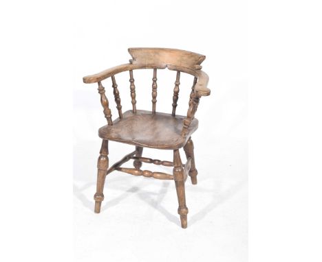 A late 19th early 20th Century elm and beech smokers elbow chair 
The outswept arms supported on ring turned spindles above a