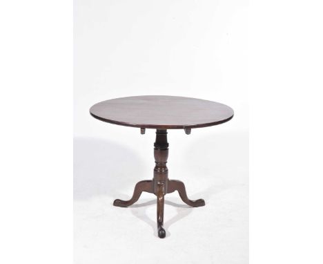 A Georgian mahogany circular tripod tableThe tilt top table raised upon a ring turned baluster shaft and three downswept supp