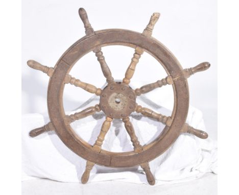 A vintage carved wooden ships wheelOf circular form the turned eight spoke wheel adorned with exterior handles and applied wi