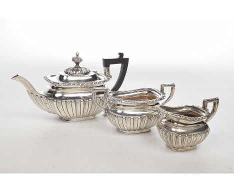 A Silver three-piece tea service To include a twin handled sugar bowl, milk jug and teapot each with fluted cobed design, J.S