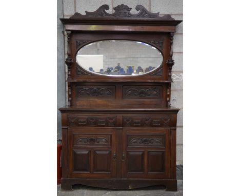A late Victorian walnut mirror back sideboardWith a shaped pediment above an oval bevelled plate flanked by two turned uprigh