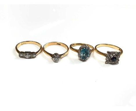 Four 18ct gold rings to include a three stone diamond ring, size J, single stone diamond ring, size K½, blue zircon and diamo