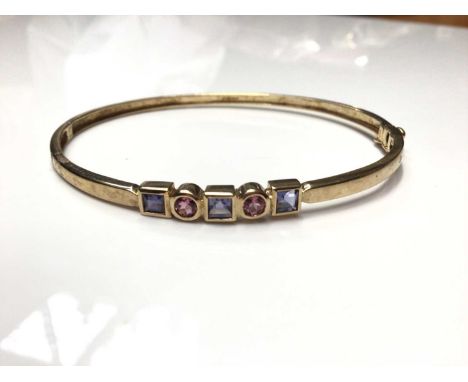 9ct gold gem set bangle with two round mixed cut pink stones interspaced with three square step cut purple stones in rub over