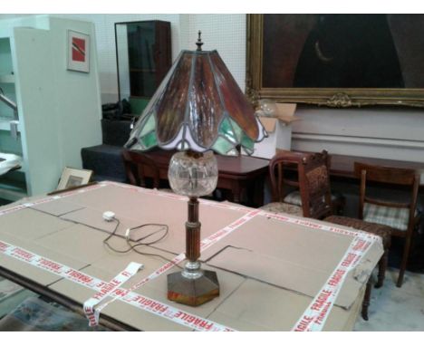 the tiffany style shade resting on an oil lamp base with a glass reservoir, wire for electricity&nbsp; 