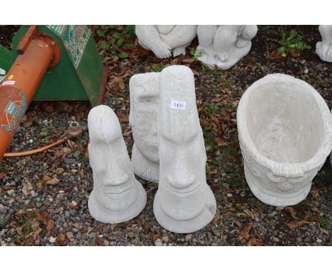 Three concrete garden ornaments in the form of Easter Island Heads