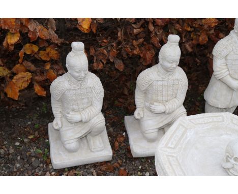 Two concrete garden ornaments in the form of kneeling warriors