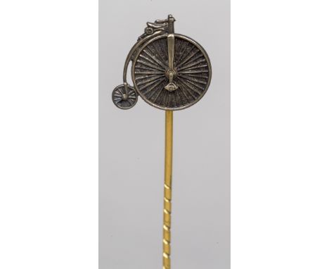 An unmarked white and yellow metal stick pinThe head formed as a penny farthing, cased; together with a seed pearl set stick 