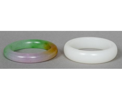 A mutton fat jade bangleOf typical form; together with another similar but coloured example.  The former 8 cm diameter.  (2) 