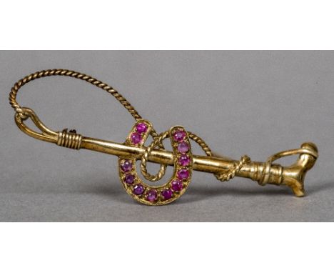 An unmarked gold ruby set bar brooch formed as riding crop and horseshoe5.5 cm wide.    CONDITION REPORTS:  Generally in good