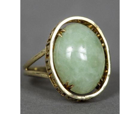 A 14 ct gold and jade ringThe central jade cabochon set in a pierced Greek key border.  2 cm high.    CONDITION REPORTS:  Gen