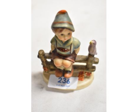 A small sized Goebel Hummel figure of boy sat on fence. Bearing a modern back stamp.