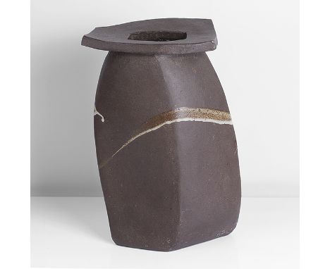 Stoneware, dry dark brown body with dark iron speckle, the distorted slab built form with broad undulating rectangular lip, m