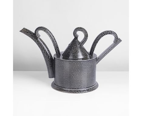Stoneware, dark greyish blue saltglaze, the body of drum form with exaggerated looping handle, spout and finial, impressed ma