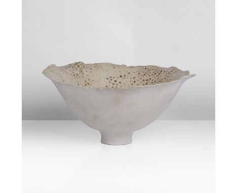 Porcelain, pale green and speckled brown glaze with undulating bands across the well, pinched undulating rim, raised on a sma
