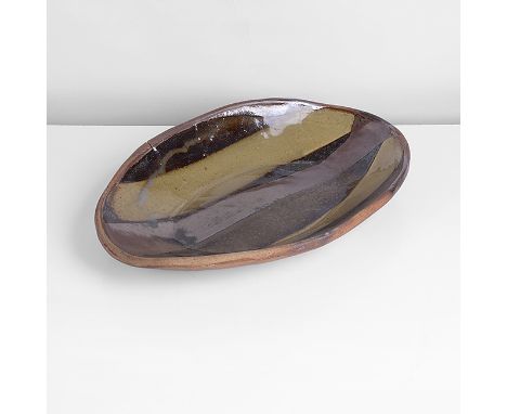 Stoneware, press moulded form, mottled brown glazes with olive green pours across the well, impressed MC and Wenford Bridge P
