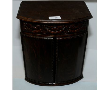 Oak smokers cabinet with internal shelf and pipe racks with upper drawer above two cupboard doors and carved swag decoration