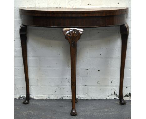 Reproduction mahogany and stained wood demi-lune card table, foldover top enclosing a baize lined interior, turned legs, pad 