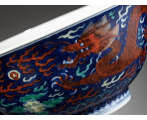 A RARE BLUE-GROUND POLYCHROME-DECORATED 'DRAGON' BOWL, QIANLONG MARK AND PERIODChina, 1736-1795. Superbly potted with deep ro