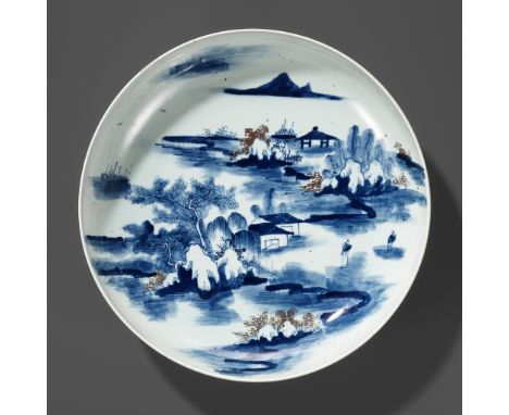 A LARGE UNDERGLAZE-BLUE AND COPPER-RED GLAZED CHARGER, KANGXI PERIODChina, 1662-1722. The shallow rounded sides supported on 