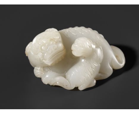 A WHITE JADE WEIGHT OF A BUDDHIST LION WITH CUB, 17TH CENTURYChina. Depicting a very interactive scene between a recumbent Bu