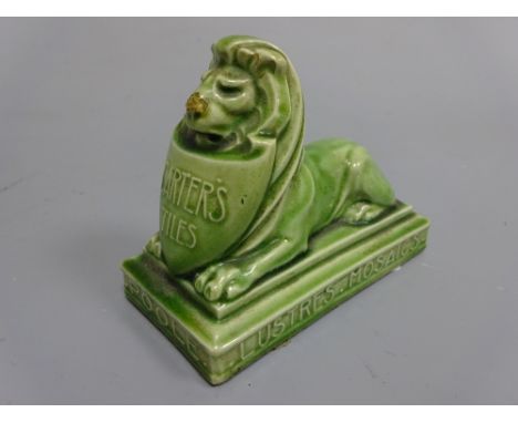 A POOLE POTTERY GREEN GLAZED STONEWARE ADVERTISING PAPERWEIGHT, modelled as recumbent lion with shield inscribed 'Carter's Ti
