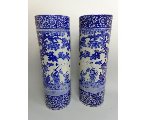 A LARGE PAIR OF CYLINDRICAL VASES/STICK STANDS, decorated in blue and white with figures in landscapes, floral and scroll str